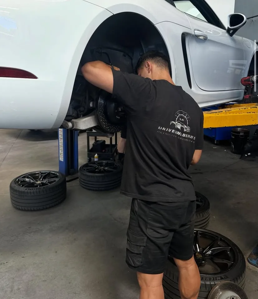 Driveline Gears mechanic working on brakes of a white Porsche